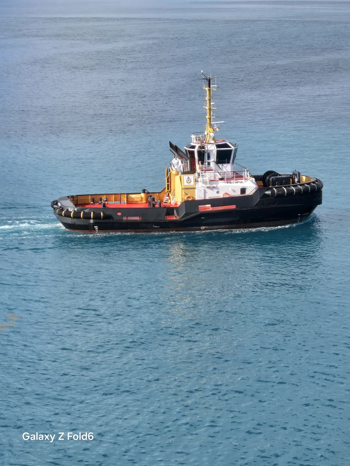 the cruise hq black and white tugboat crossing turquoise water at royal naval dockyard bermuda