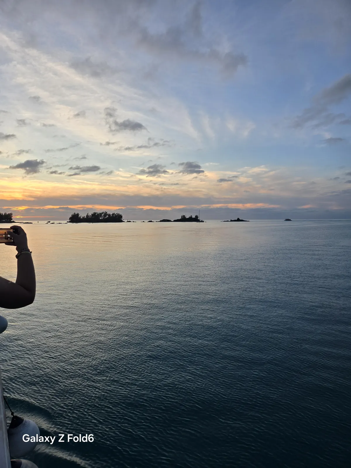 the cruise hq small islands on the horizon of bermuda's great sound at dusk as a guest takes a photo