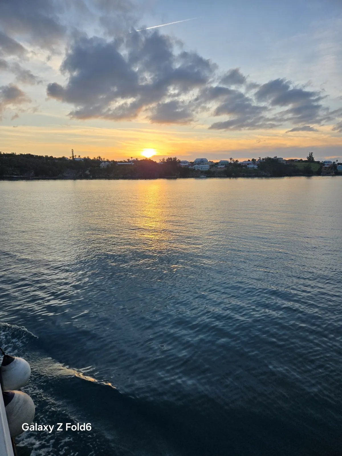 the cruise hq sun setting behind bermuda homes along the shoreline of the great sound