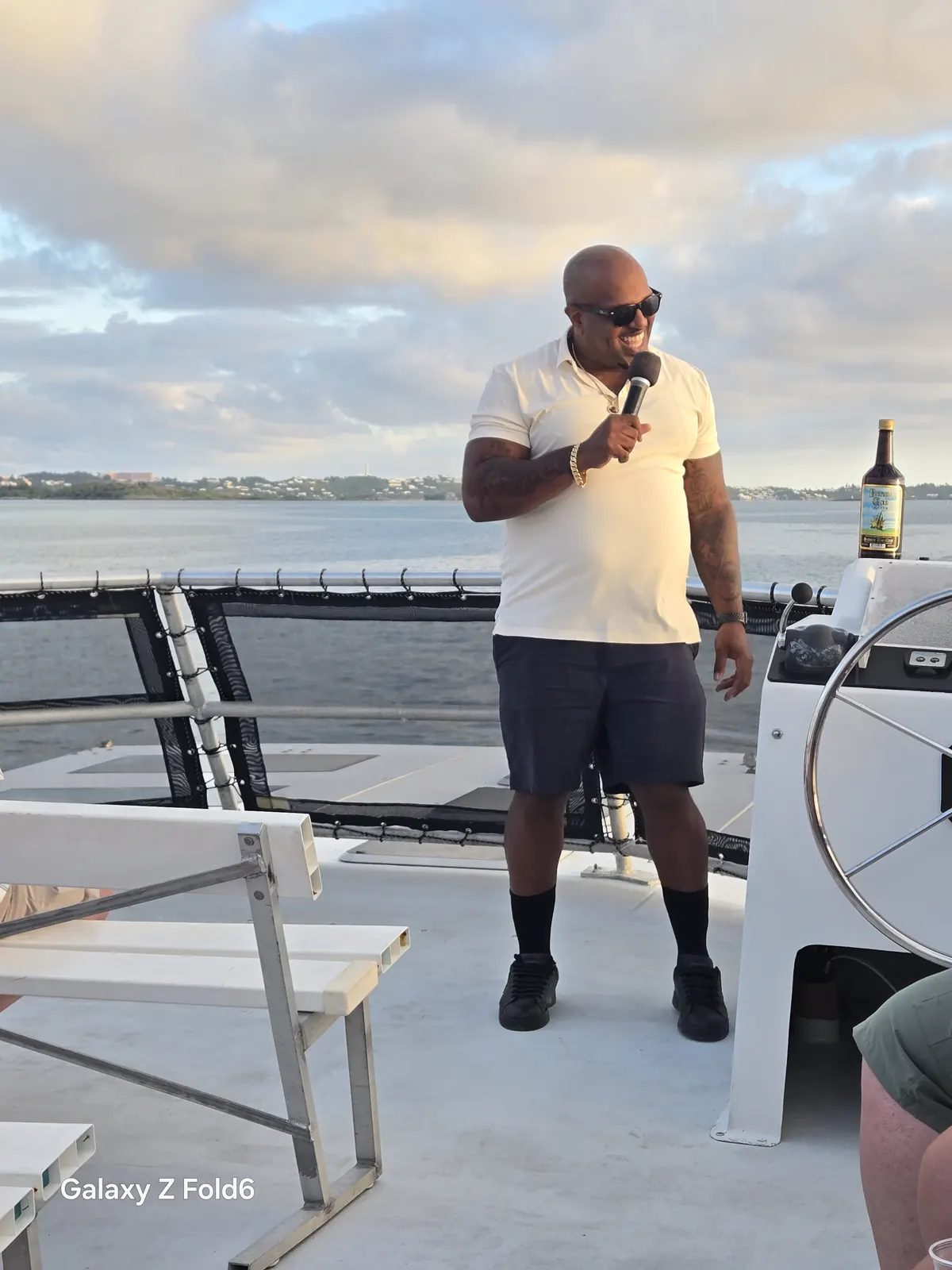 the cruise hq rum cruise host speaking into a microphone on the deck of a catamaran in bermuda's great sound