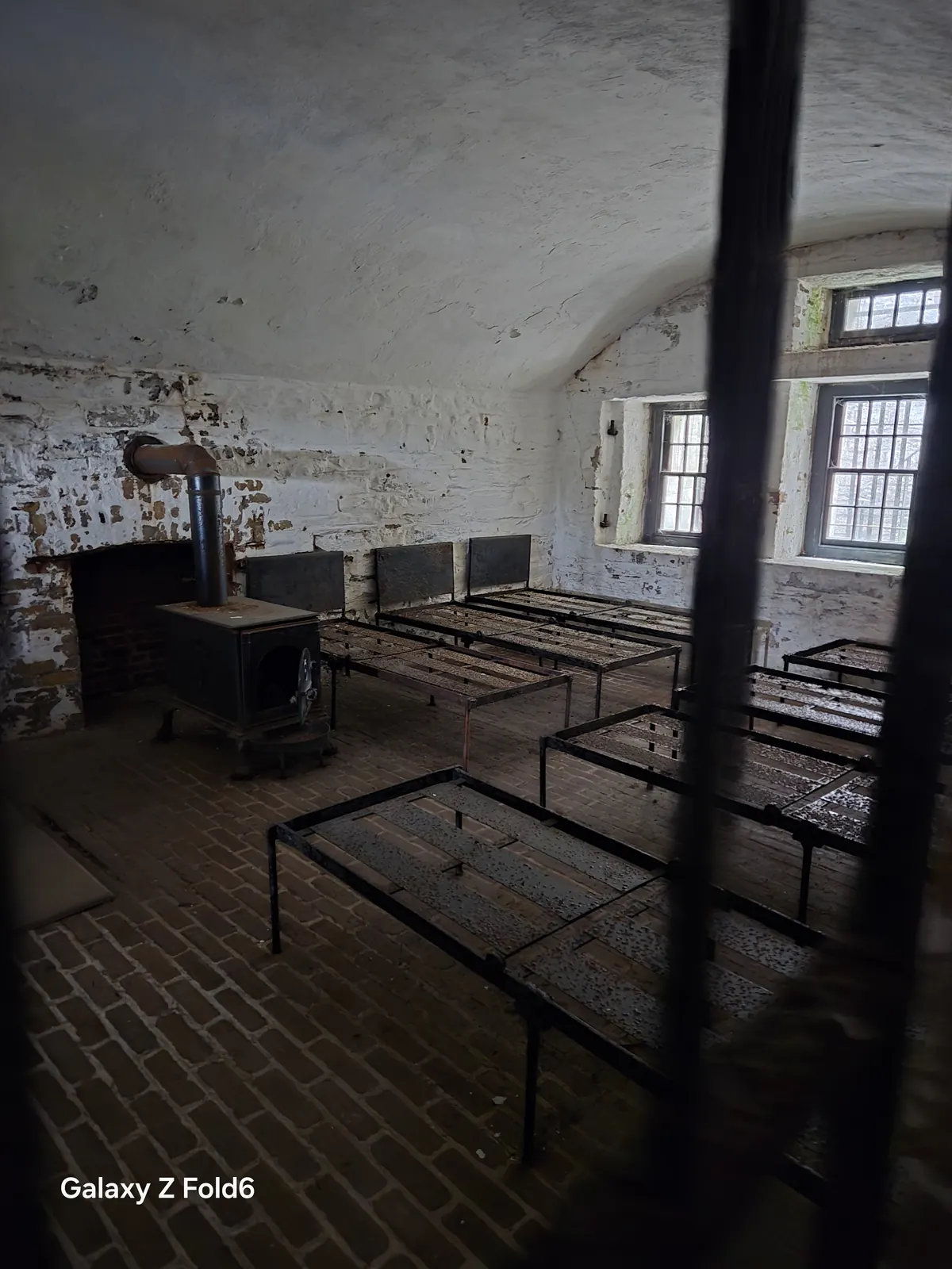 the cruise hq barrack room with iron bed frames and a wood stove at halifax citadel