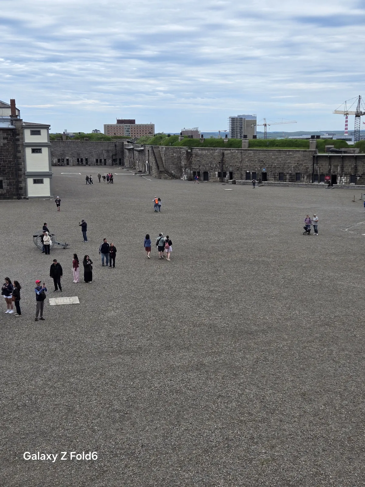 the cruise hq visitors walking across the wide gravel parade square at halifax citadel