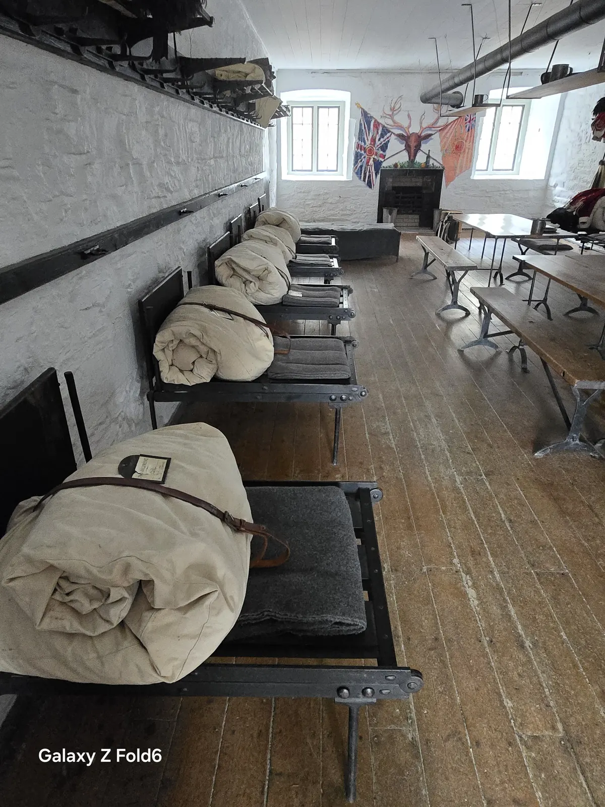 the cruise hq barrack room with rolled bedding on iron beds and flags on the wall at halifax citadel