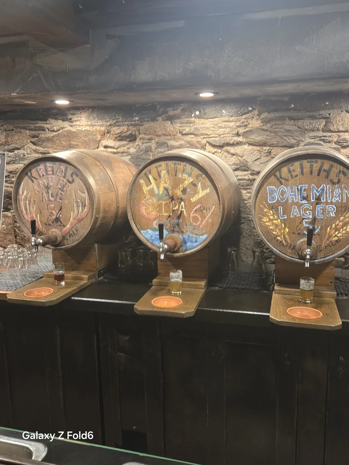 the cruise hq three painted beer barrels including a hazy ipa on the stone walled bar at alexander keith's Brewery in Halifax