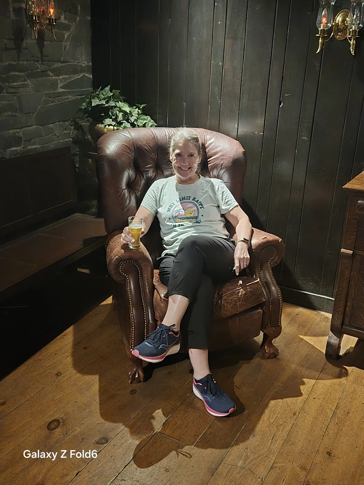 the cruise hq smiling visitor with a beer in a tufted leather armchair at alexander keith's Brewery in Halifax