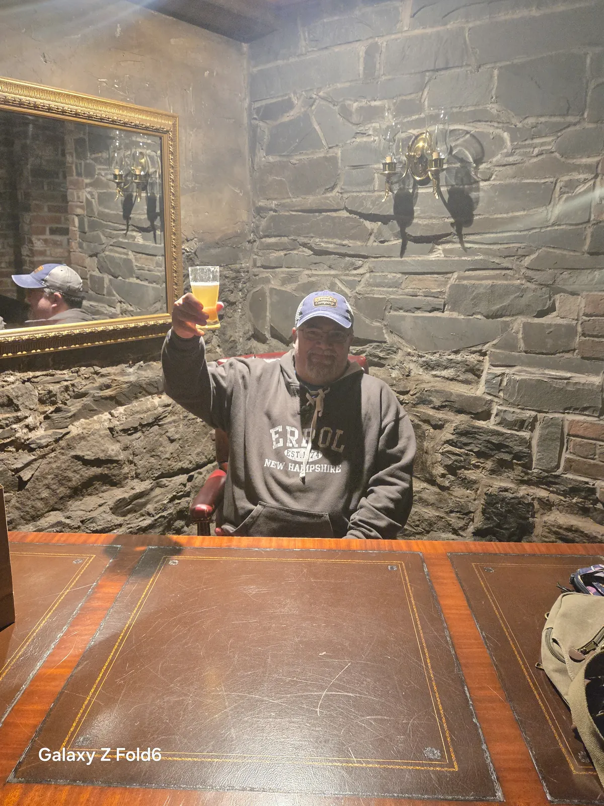 the cruise hq visitor raising a glass of beer at a leather topped desk in a stone walled room at alexander keith's Brewery in Halifax