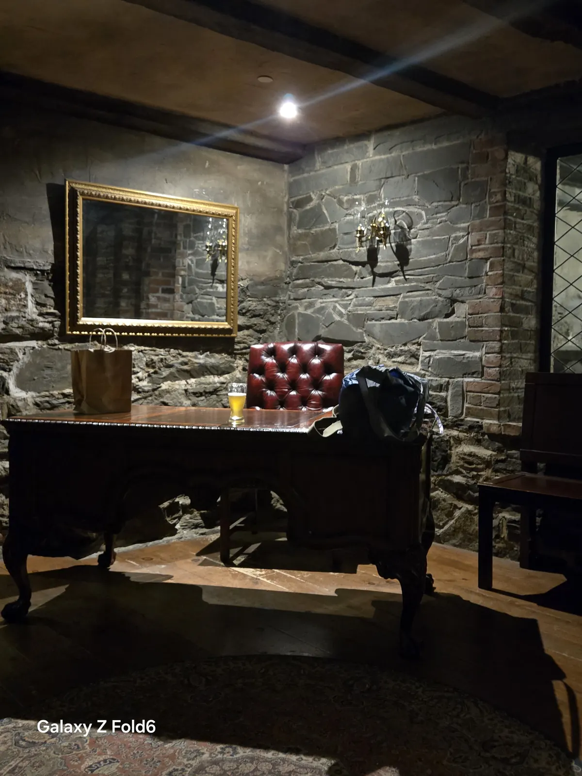 the cruise hq antique desk and red leather chair below a gilt mirror in a stone walled room at alexander keith's Brewery in Halifax