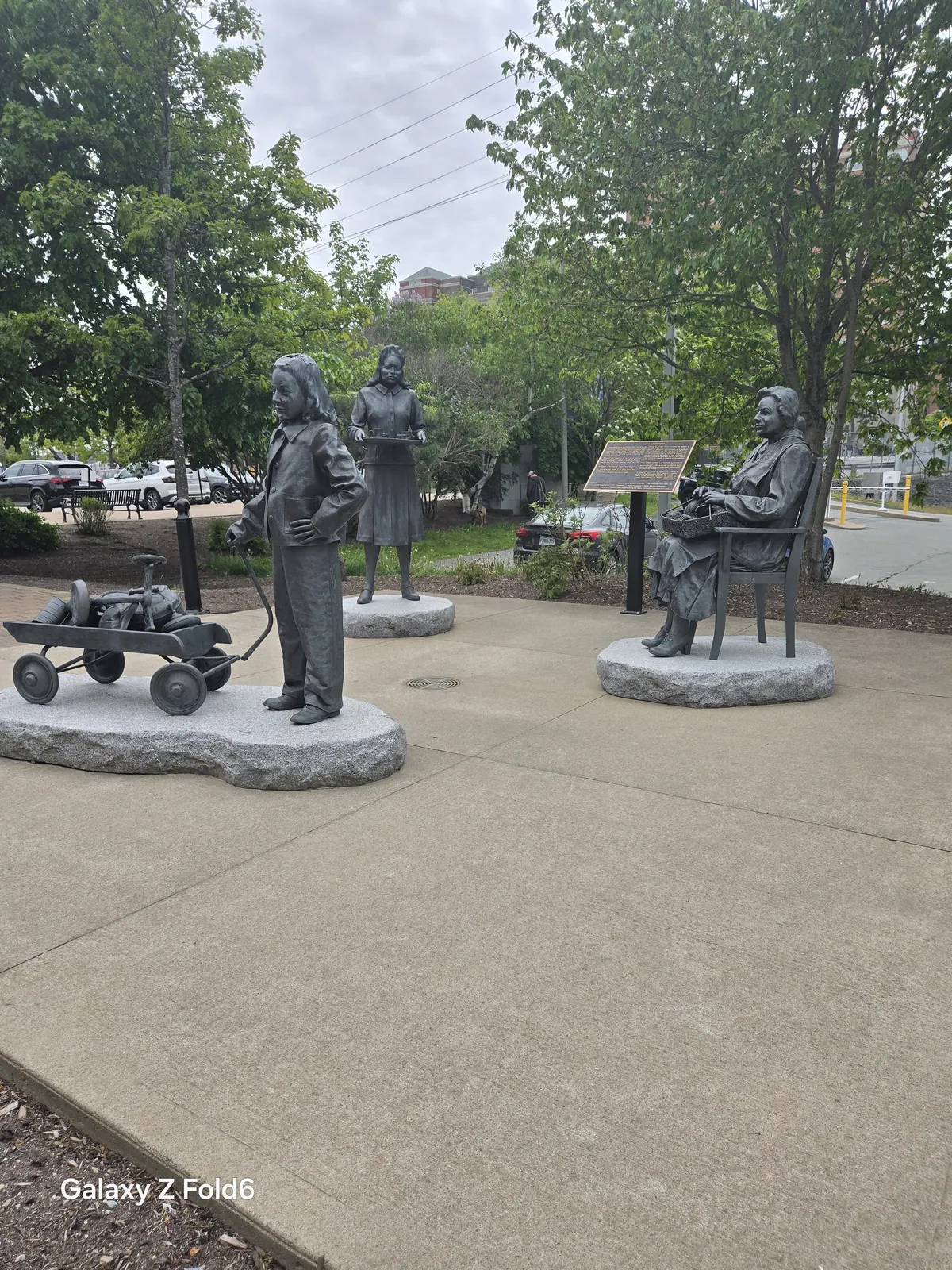 the cruise hq bronze statues of a girl with a wagon of scrap metal a woman serving food and a seated woman knitting on the halifax waterfront