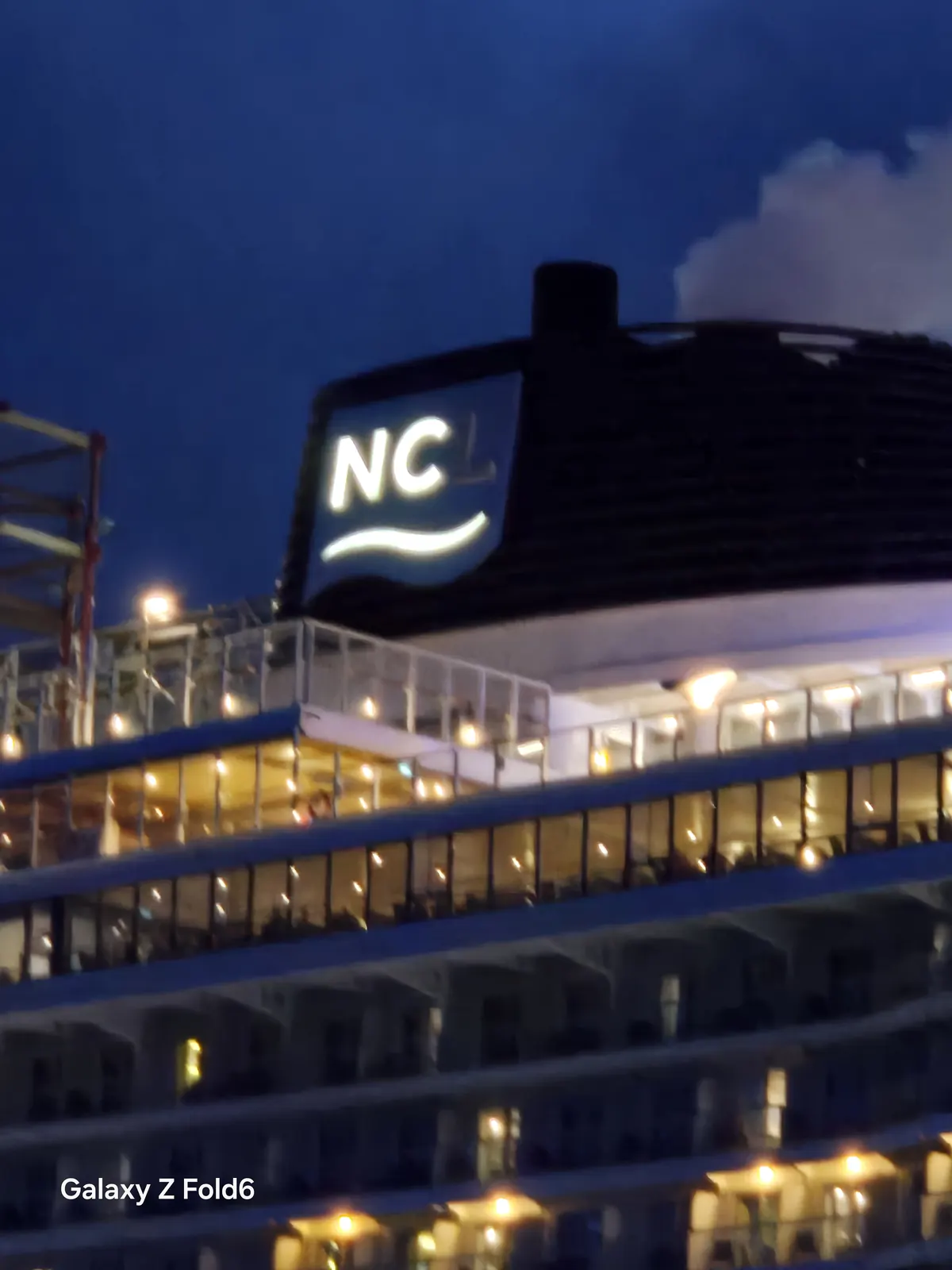 the cruise hq illuminated ncl logo on the funnel of norwegian breakaway at night